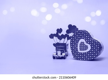 Gift Box And Retro Car With Paper Hearts On A Very Peri Background. Valentine's Day Concept, Anniversary, Mother's Day And Happy Birthday Greeting, Copyspace, Close Up