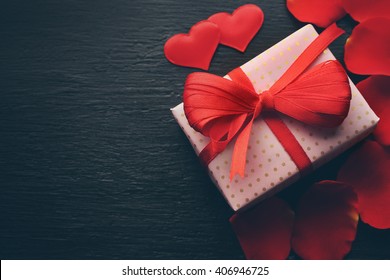 Gift box, rose petals and decorative hearts on wooden background - Powered by Shutterstock