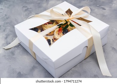 Gift box with tasty cupcakes. Present box full of fruit cupcakes. Birthday party. Easter or christmas holidays celebrate. Holidays cupcakes with strawberry and blueberry. Delivery. Sweet shop.