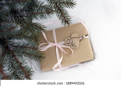 gift box tied with a ribbon, heart in the snow on the background of fir branches