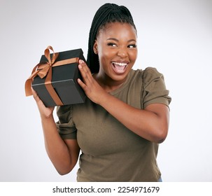 Gift, box and woman guess in studio with package, smile and celebration. Happy, curious and black female with present, surprise and ribbon on background, birthday and giveaway of product promotion - Shutterstock ID 2254971679