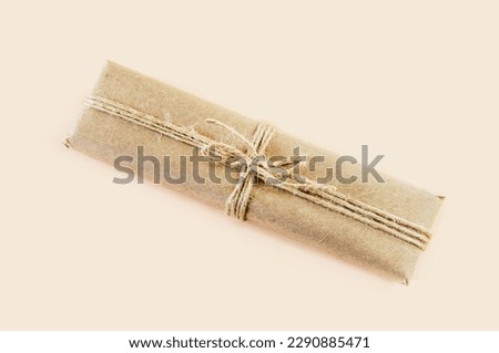 gift box wrapped in kraft paper and tied with twine on a beige background. Top view. Vintage gift box made of brown eco-paper, tied with a rope.