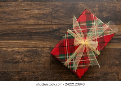 Gift box wrapped in plaid wrapping paper with gold bow. Copy space to left.  - Powered by Shutterstock