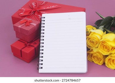 Gift boxes and blank notebook with yellow roses on purple background. Birthday and gift concept.