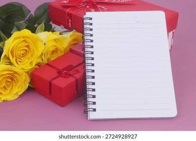 Gift boxes and blank notebook with yellow roses on purple background. Birthday and gift concept.