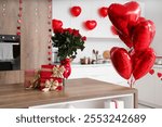 Gift boxes and bouquet of roses on wooden table in kitchen, closeup. Valentine