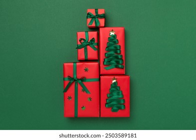 Gift boxes in Christmas tree shape on color background, top view