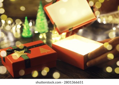 Gift boxes with a large red bow  against a background bokeh of twinkling party lights. Luxury New Year gift. Christmas gift. Christmas background with gift box. Christmastime celebration