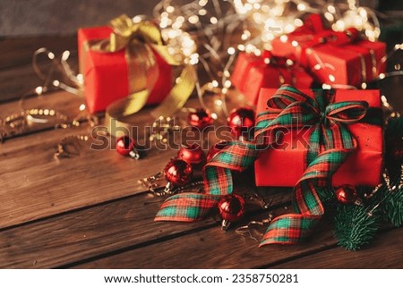 Gift boxes with a large red bow against a background bokeh of twinkling party lights. Luxury New Year gift. Christmas gift. Christmas background with gift box. Christmastime celebration