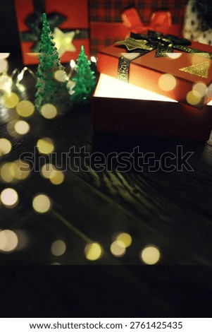 Gift boxes with a large red bow  against a background bokeh of twinkling party lights. Luxury New Year gift. Christmas gift. Christmas background with gift box. Christmastime celebration