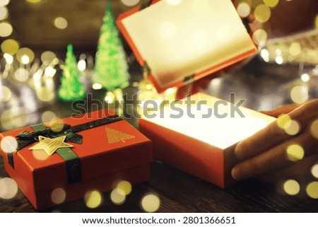 Gift boxes with a large red bow  against a background bokeh of twinkling party lights. Luxury New Year gift. Christmas gift. Christmas background with gift box. Christmastime celebration