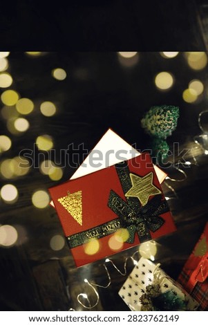 Gift boxes with a large red bow  against a background bokeh of twinkling party lights. Luxury New Year gift. Christmas gift. Christmas background with gift box. Christmastime celebration
