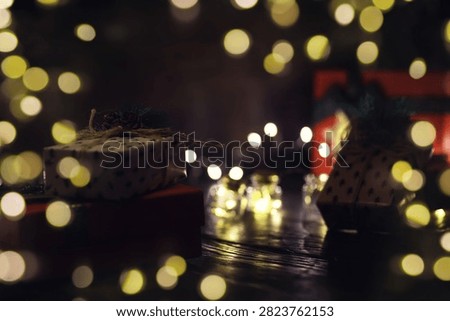 Gift boxes with a large red bow  against a background bokeh of twinkling party lights. Luxury New Year gift. Christmas gift. Christmas background with gift box. Christmastime celebration