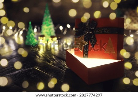 Gift boxes with a large red bow  against a background bokeh of twinkling party lights. Luxury New Year gift. Christmas gift. Christmas background with gift box. Christmastime celebration