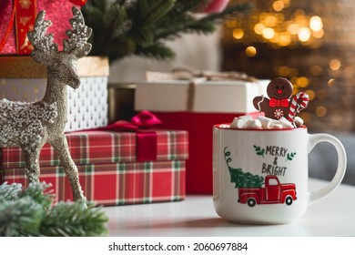 Gift boxes, a mug of hot cocoa, marshmallows and a gingerbread man on the table in the home interior of the living room. Cozy concept of Christmas and winter holidays 2022. - Powered by Shutterstock