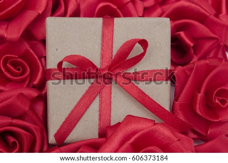 Gift boxes with red satin ribbons and red satin roses in the background