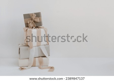 Gift boxes stack over white wall. Festive Christmas, New Year holidays celebration concept with blank mockup copy space