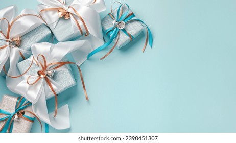 Gift boxes wrapped in blue, white and silver paper with white, blue and gold ribbon bows. Blue background, top view. Christmas and New Year gifts, Boxing Day. - Powered by Shutterstock