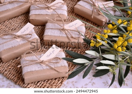 Gift boxes wrapped craft paper jute ribbon and thank you tag, rustic wedding favors country theme decoration, wicker background, green leaves yellow flowers, spring summer autumn style event souvenirs