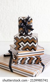 Gift boxes wrapped in Striped and chevron geometric paper with black ribbon bows near black and white decor close up. Christmas, New Year, Birthday, Anniversary concept