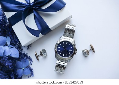 Gift Concept For Men. Men's Accessories. Blue Flowers, Gift Box With Blue Bow, Mens Watch And Cufflinks Isolated On White Background. Father's Day 