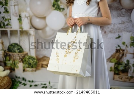 A gift from godparents for the first holy communion. A girl in a white communion dress with gifts