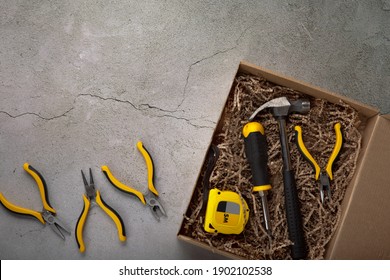 A Gift For A Man For The Holiday. Tool Box: Hammer, Screwdriver, Tape Measure, Pliers And Dried Fish On A Gray Background. View From Above