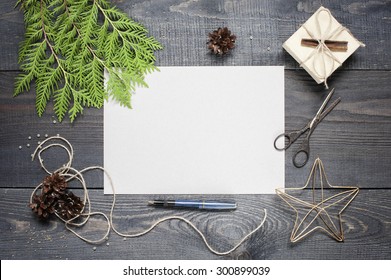 Gift, postcard, pine cones, thuja and cinnamonin on the dark wooden textured table