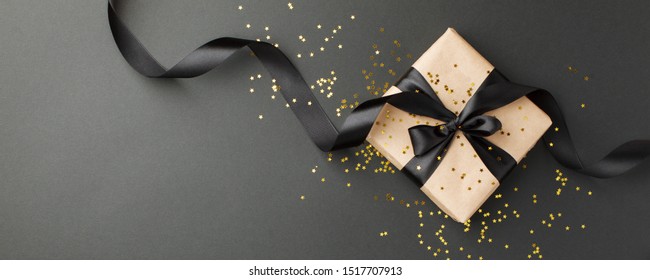 Gift Or Present Box And Gold Stars Confetti On Black Table Top View. Flat Lay Composition For Birthday, Mother Day, Black Friday Sale, Xmas, Christmas, New Year 2022 Or Wedding.