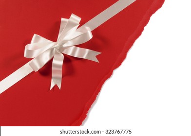 Gift Ribbon Bow In White Satin On Untidy Torn Red Paper Background