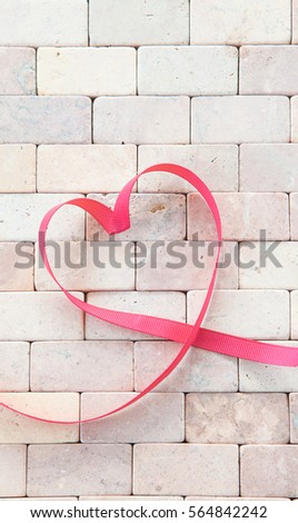 Gift ribbon in a heart shape on rustic stone background