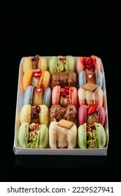 Gift set of large colored macaroons with different fillings and decorations, on a black isolated background. Confectionery concept.