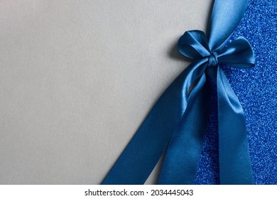 Gift silver shiny card, certificate or texture gift box with dark blue ribbon bow. Christmas, new year, birthday, anniversary or sale background. Top view, flat lay, copy space, template for design