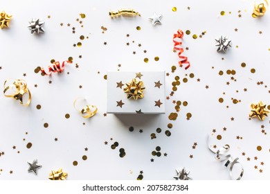 Gift white box with a gold tape with tinsel and confetti on a white background. The concept of a gift, a new year, a festive background. Flat lay, top view