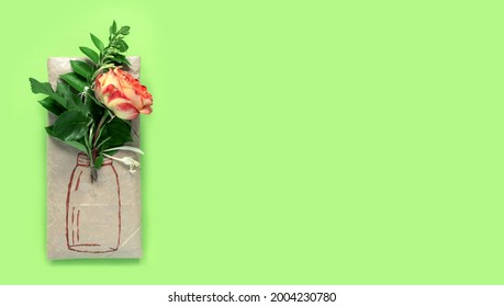 Gift wrapped in wrapping paper and bouquet red yellow  roses   painted vase  Honeysuckle branches for decoration  green background  Conceptual creative present   Flat lay  top view concept 