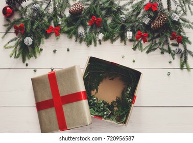 Gift Wrapping Background. Open Box For Christmas Present In Paper Decorated With Satin Ribbon. Winter Holidays Concept. Top View Of White Wood Table With Fir Tree Branches, Ornaments And Garlands