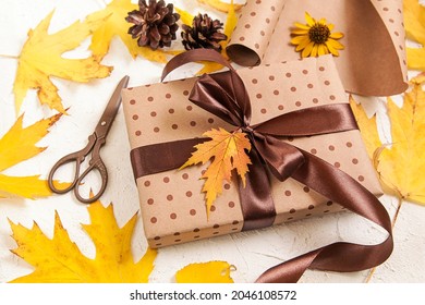 Gift Wrapping. Brown paper gift box with yellow dried leaves on white. Autumn creative holiday present. Thanksgiving day, fall background. - Powered by Shutterstock