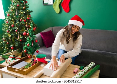 Gift wrapping. Hispanic young woman getting ready to put the christmas gifts under the tree at home  - Powered by Shutterstock