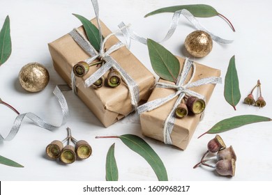 Gifts, Australian Native Eucalyptus Leaves & Gum Nuts On A Wooden Background. Presents Wrapped In Silver Ribbon & Rustic Twine. Christmas, Birthday, Valentines Day, Anniversary Or Mothers Day.