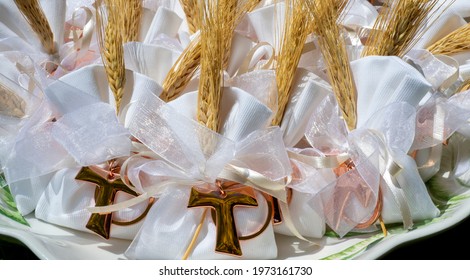 Gifts Or Favors For The First Or Holy Communion. Small Bags Of White Fabric With Ear Of Wheat And Tau Christian Cross. Religious Symbol