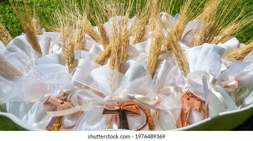 Gifts Or Favors For The First Or Holy Communion. Small Bags Of White Fabric With Ear Of Wheat And Tau Christian Cross. Religious Symbol