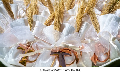 Gifts Or Favors For The First Or Holy Communion. Small Bags Of White Fabric With Ear Of Wheat And Tau Christian Cross. Religious Symbol