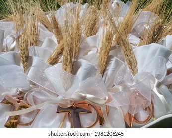 Gifts Or Favors For The First Or Holy Communion. Small Bags Of White Fabric With Ear Of Wheat And Tau Christian Cross. Religious Symbol