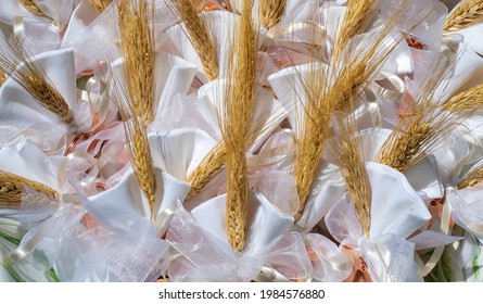 Gifts Or Favors For The First Or Holy Communion. Small Bags Of White Fabric With Ear Of Wheat And Tau Christian Cross. Religious Symbol