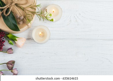 Geschenke und Blumen auf Holzhintergrund. Draufsicht, flach gelegene Lage mit hellen Kerzen und Blättern