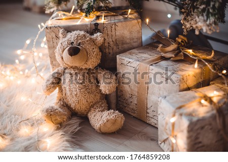 Gifts under the Christmas tree for Christmas. Brown bear soft toy, next to gift boxes in a decorated room. Family tradition, gifts from Santa Claus