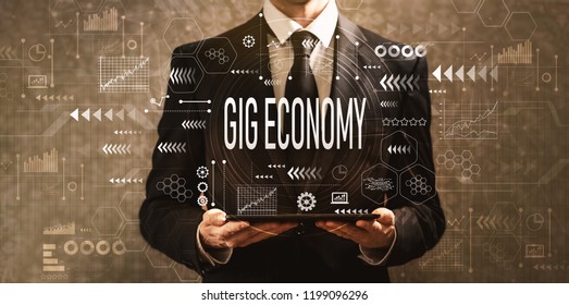 Gig economy with businessman holding a tablet computer on a dark vintage background - Shutterstock ID 1199096296