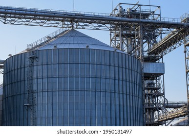 Gigantic Metal Silo (huge Metal Tank For Sugar, Silage Or Grain Storage) And Other Industrial Equipment Of Modern Sugar Factory, Blue Sky In The Background