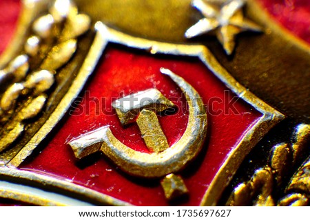 Gilded symbol of communism on a red background.