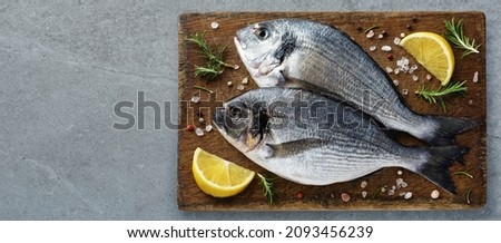 Gilt-head bream (dorade) lemon and rosemary on a cutting board. Top view.